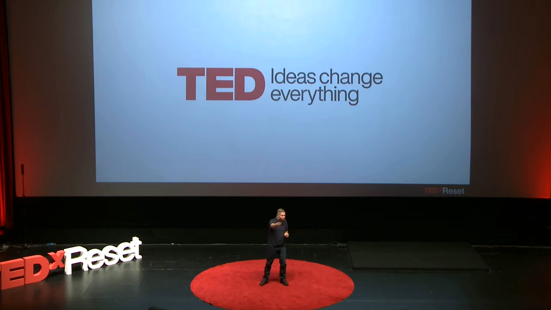 Ziya Şakir Yılmaz, TEDxReset 2025 O An konuşmasında; TED ekranı ve TEDxReset harfleri sahnede